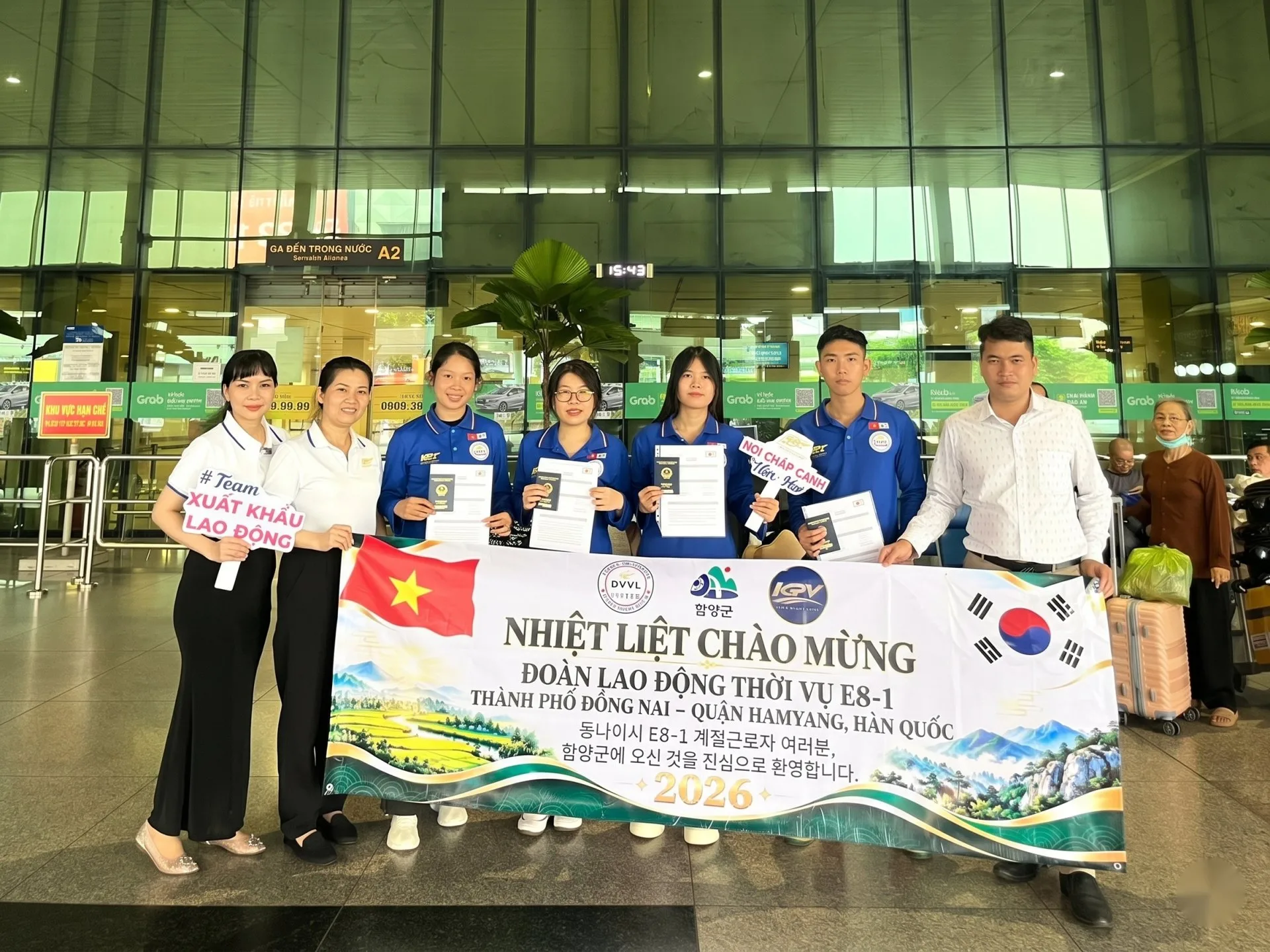 Nhóm cầm hộ chiếu và băng rôn chào mừng đoàn lao động thời vụ E8-1 Quận Hamyang tại sân bay, KPV – Hàn Quốc