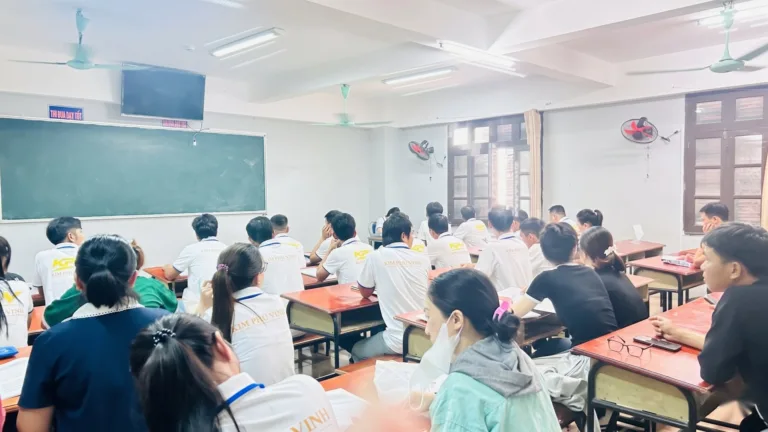 Học viên áo đồng phục trắng có chữ KPV ngồi trong lớp nhìn lên bảng xanh – chương trình thực tập sinh cùng KPV
