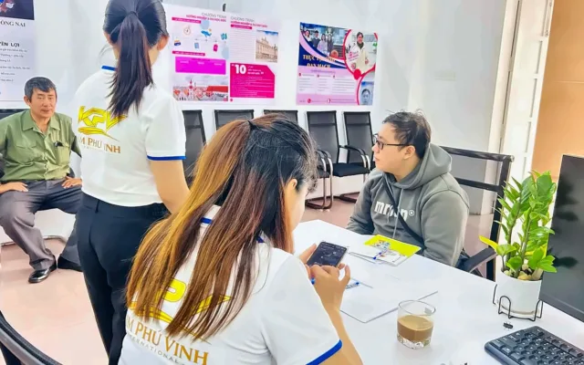 Hai nhân viên áo KPV tiếp một khách tại bàn, sau lưng là poster du học Đức – hoạt động định hướng, tư vấn tại KPV
