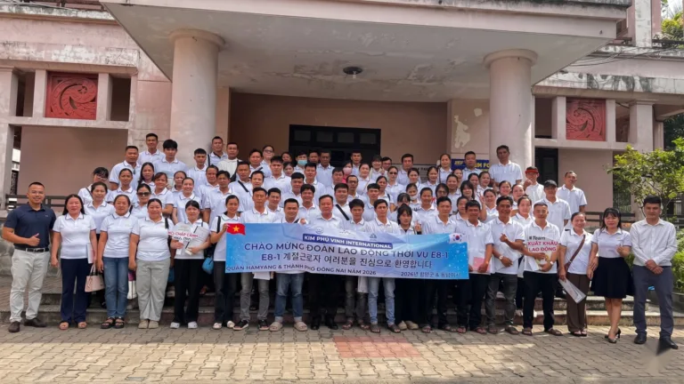 Ảnh tập thể đông người áo trắng cầm băng rôn chào mừng đoàn E8-1 trước tòa nhà – việc làm quốc tế, trong nước cùng KPV