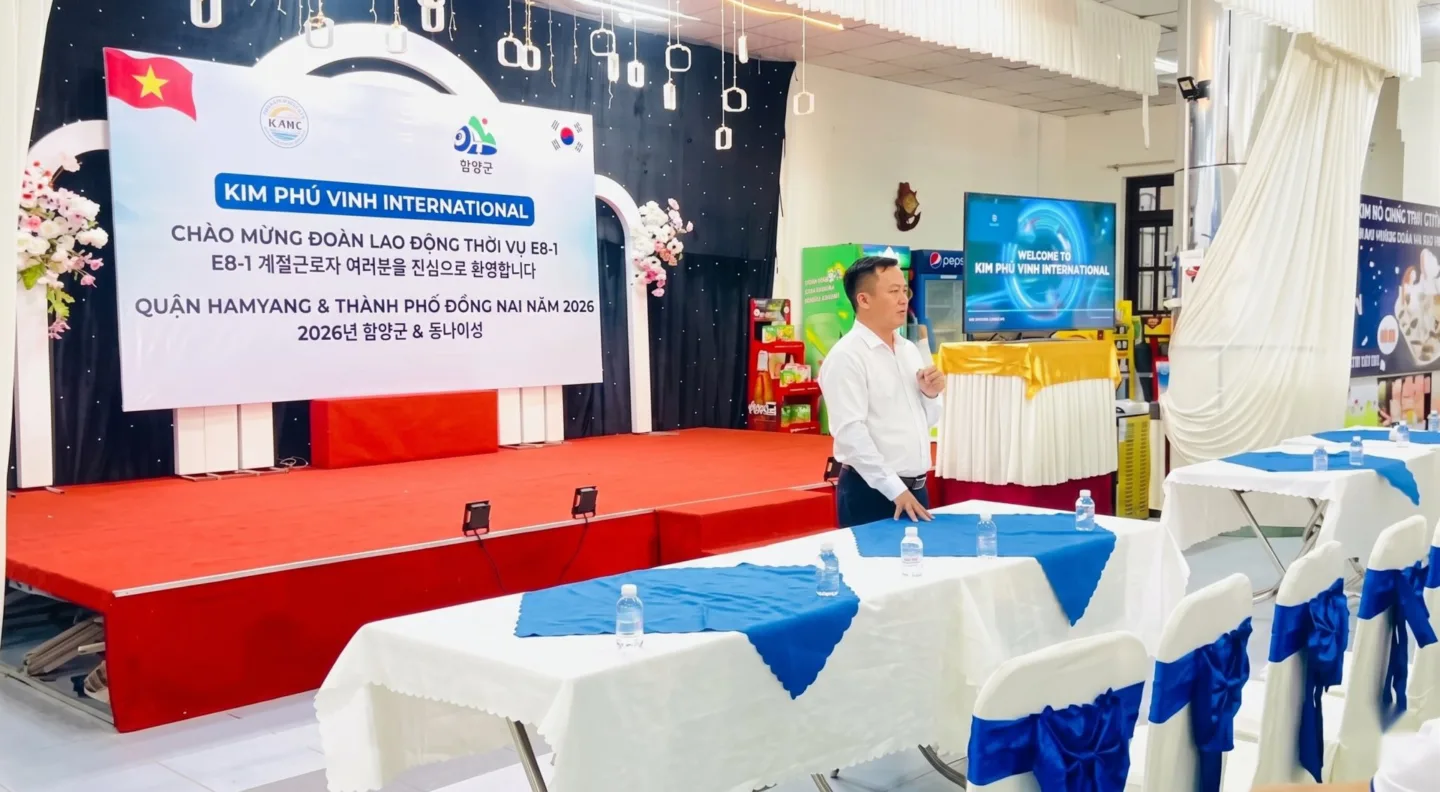 Người áo sơ mi trắng phát biểu trong hội trường có phông chào mừng đoàn E8-1 – không gian học tập, tư vấn tại KPV